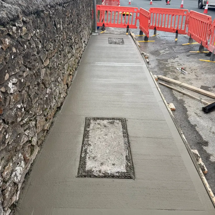 New concrete path beside a stone boundary wall