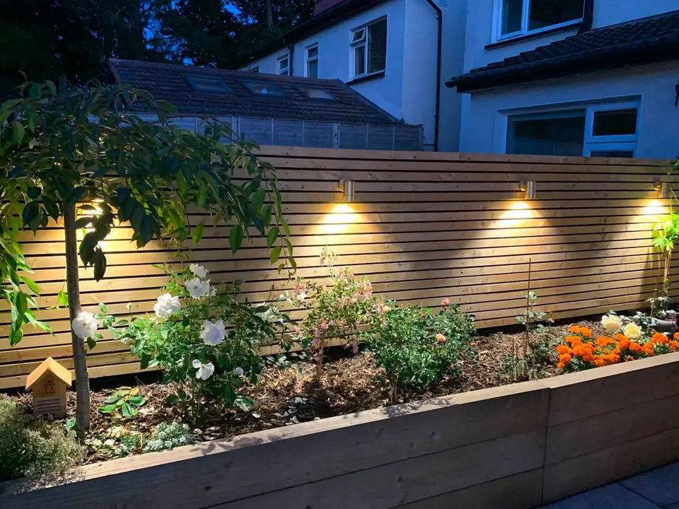 JK Electrical warm garden-fence downlights above planted raised beds