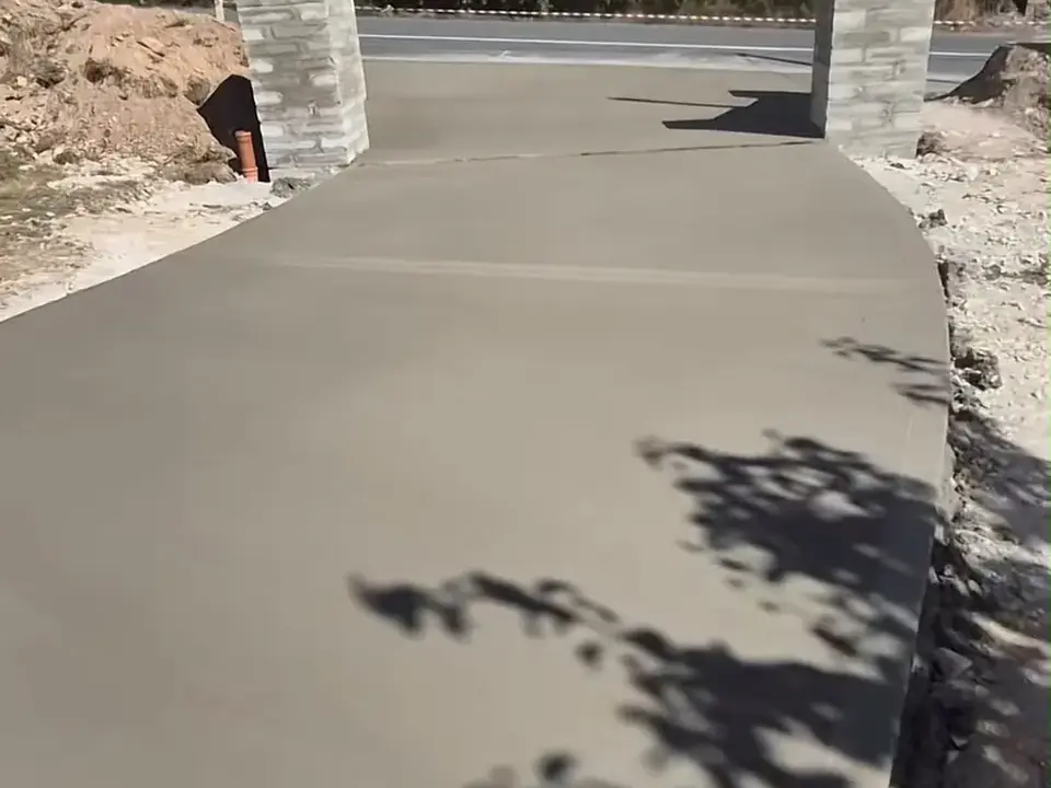 Fresh concrete driveway and entrance between stone pillars