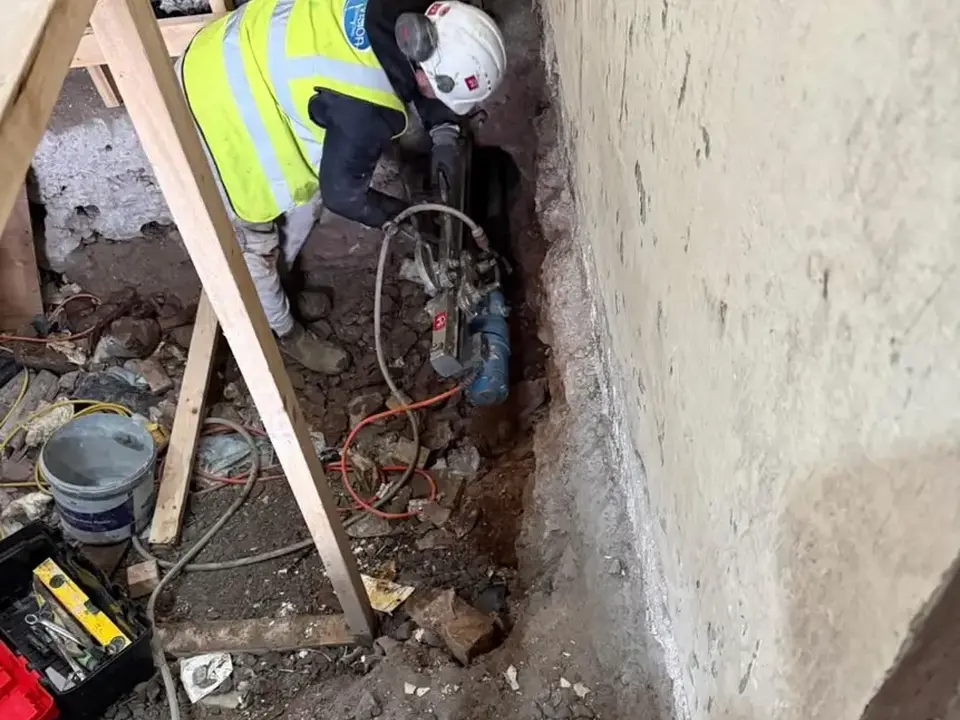 Core drilling equipment working beside a masonry wall