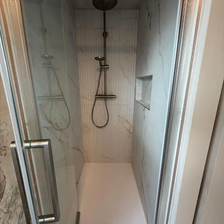 Walk-in shower installation with rainfall shower and glass enclosure by PrimeLine Plumbing Solutions