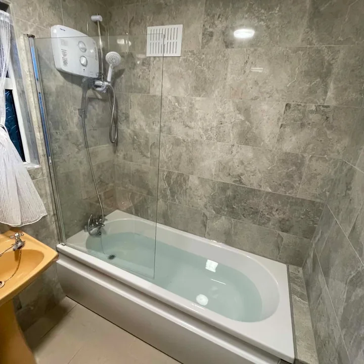 Complete bathroom fitout with bath, shower screen and stone-effect tiling